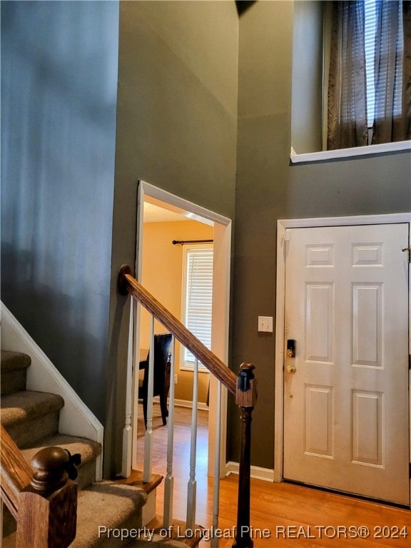 foyer with light hardwood / wood-style floors and a towering ceiling