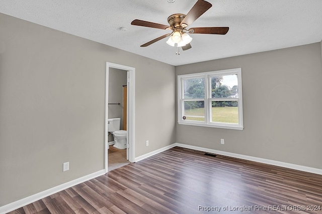 unfurnished bedroom with ceiling fan, connected bathroom, a textured ceiling, and dark hardwood / wood-style floors