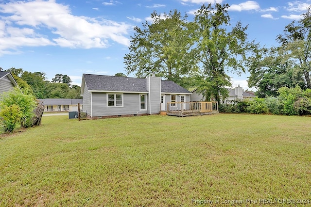 rear view of property featuring a wooden deck and a lawn