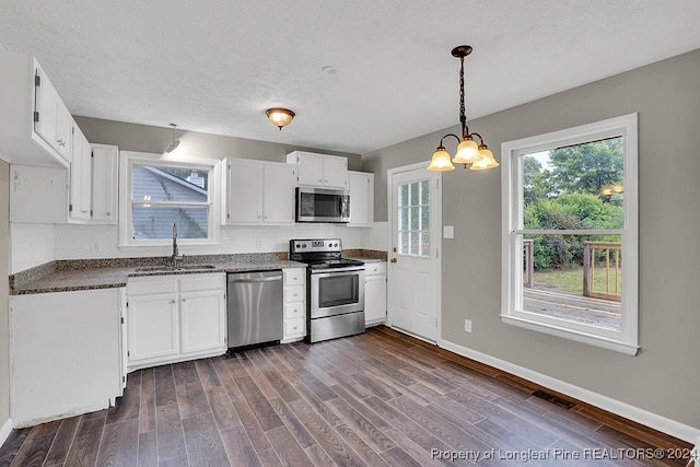 kitchen with appliances with stainless steel finishes, sink, white cabinetry, and a healthy amount of sunlight