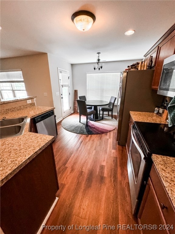 kitchen with appliances with stainless steel finishes, sink, and dark wood-type flooring