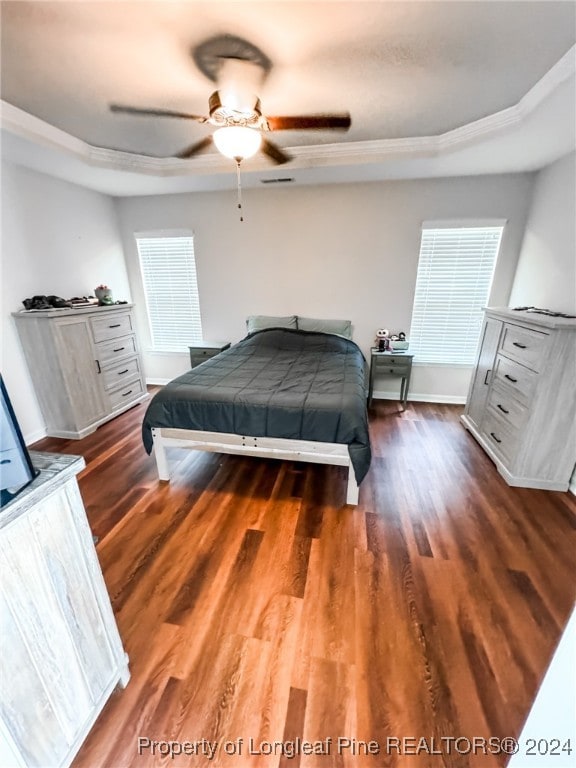 bedroom featuring ceiling fan, a tray ceiling, and dark hardwood / wood-style floors