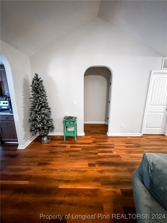 unfurnished room featuring lofted ceiling and dark hardwood / wood-style floors