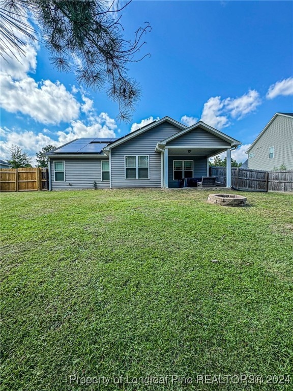 rear view of house with a fire pit, a yard, and a patio area