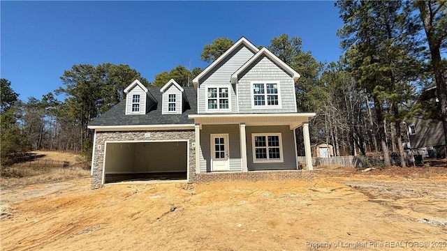 view of front of property with a porch, stone siding, and an attached garage