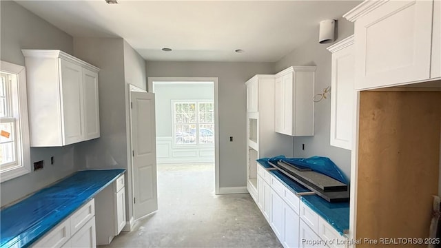 kitchen with white cabinetry and unfinished concrete flooring