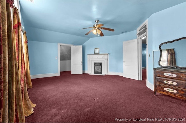 interior space featuring ceiling fan, lofted ceiling, and dark colored carpet