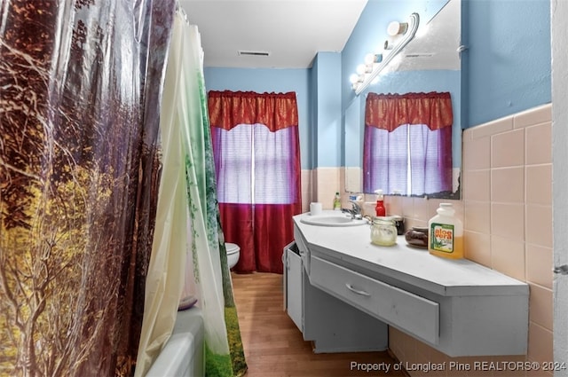 full bathroom featuring tile walls, vanity, shower / bath combination with curtain, wood-type flooring, and toilet