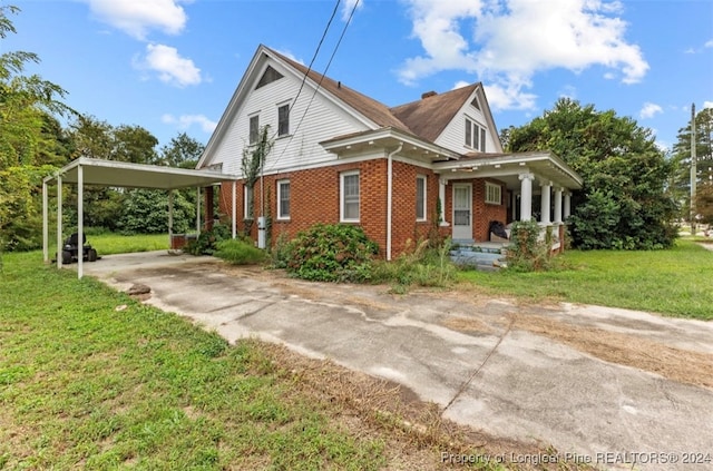 farmhouse with a carport, a porch, and a front yard