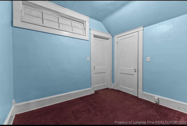 carpeted spare room with lofted ceiling