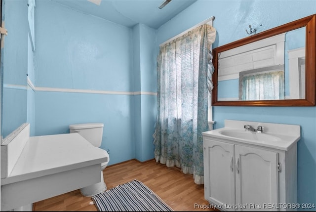 bathroom featuring wood-type flooring, vanity, and toilet