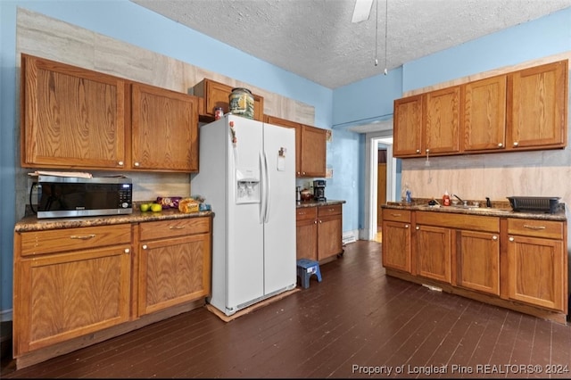 kitchen featuring white fridge with ice dispenser, a textured ceiling, dark hardwood / wood-style floors, sink, and ceiling fan