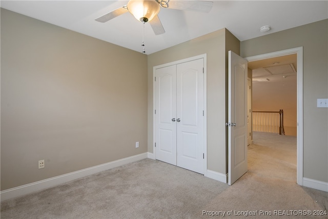 unfurnished bedroom with light carpet, a closet, and ceiling fan