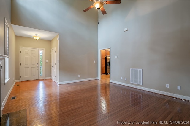 interior space featuring ceiling fan, wood-type flooring, and a towering ceiling