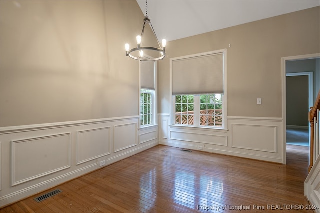 unfurnished dining area with hardwood / wood-style flooring and an inviting chandelier