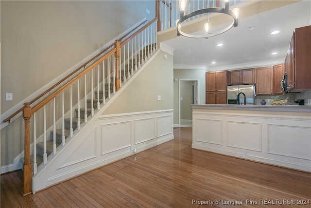 kitchen featuring stainless steel fridge with ice dispenser, an inviting chandelier, ornamental molding, and wood-type flooring