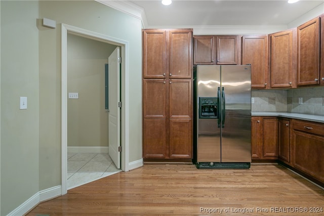 kitchen featuring decorative backsplash, stainless steel fridge, light wood-type flooring, and ornamental molding