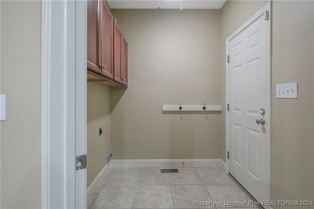 washroom featuring hookup for an electric dryer, light tile patterned floors, and cabinets