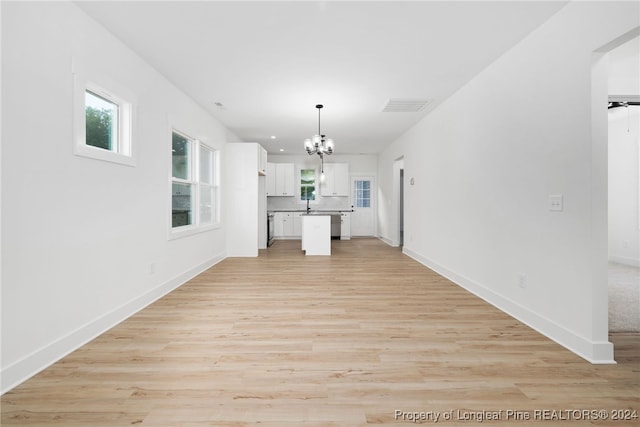 unfurnished living room featuring sink, a notable chandelier, and light hardwood / wood-style floors