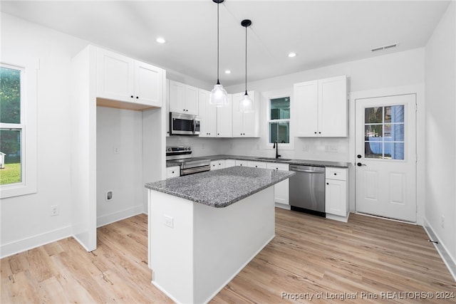 kitchen featuring a kitchen island, appliances with stainless steel finishes, a healthy amount of sunlight, and white cabinets