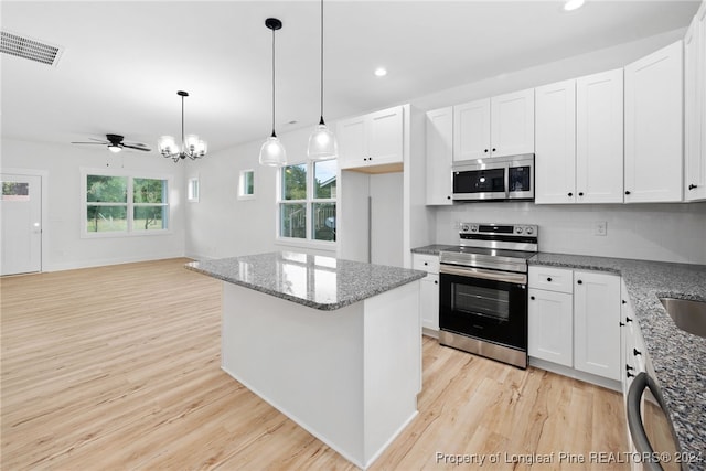 kitchen with hanging light fixtures, appliances with stainless steel finishes, white cabinetry, light hardwood / wood-style flooring, and a center island