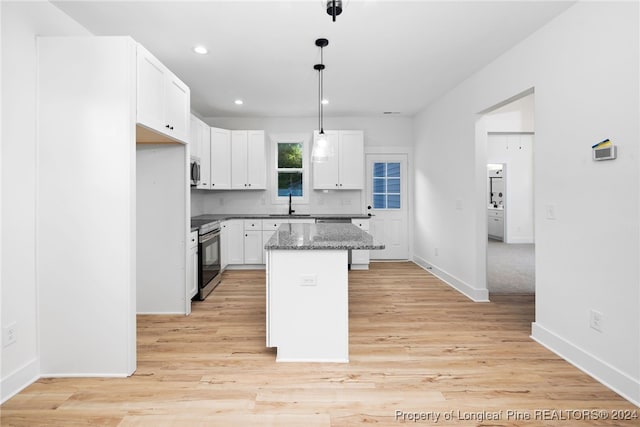 kitchen featuring white cabinets, a kitchen island, stainless steel appliances, decorative light fixtures, and light stone counters