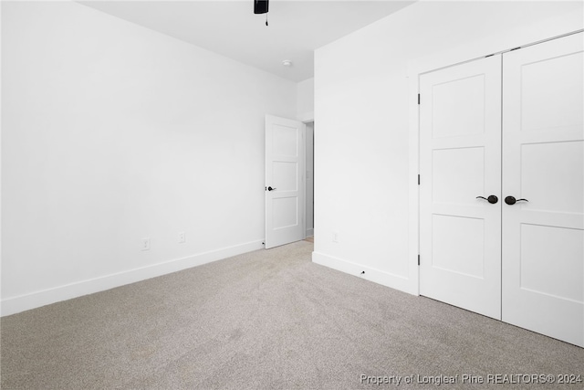 unfurnished bedroom featuring a closet, light colored carpet, and ceiling fan