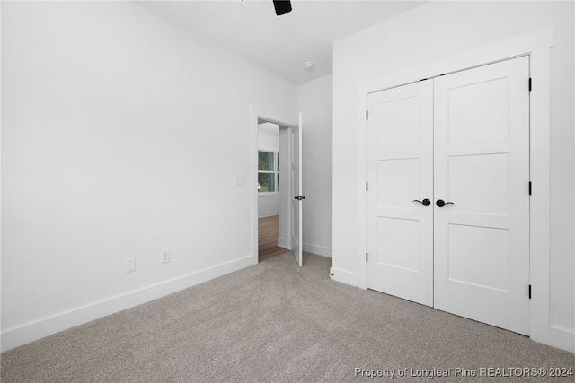 unfurnished bedroom with a closet, light carpet, and ceiling fan