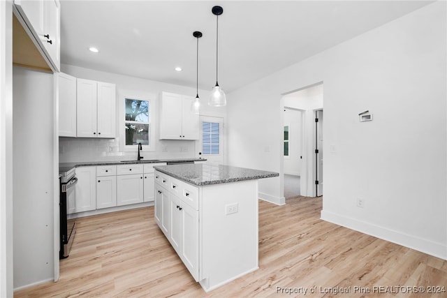 kitchen with light hardwood / wood-style floors, stainless steel range with electric stovetop, a center island, and white cabinets