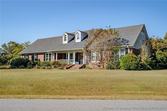 cape cod home featuring covered porch and a front lawn