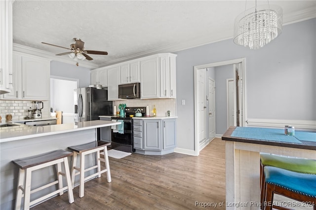 kitchen featuring pendant lighting, white cabinets, dark hardwood / wood-style floors, a kitchen bar, and stainless steel appliances