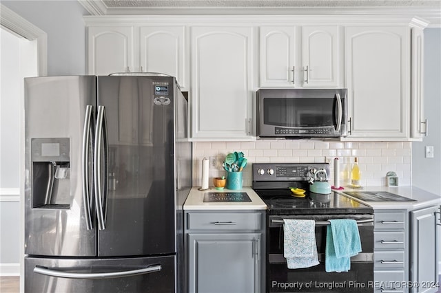 kitchen with white cabinets, backsplash, and appliances with stainless steel finishes