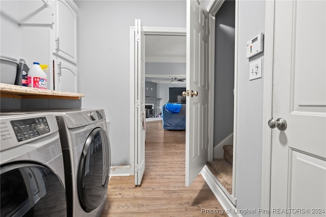 laundry room with ceiling fan, cabinets, crown molding, washer and dryer, and light wood-type flooring