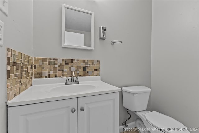 bathroom with vanity, decorative backsplash, and toilet