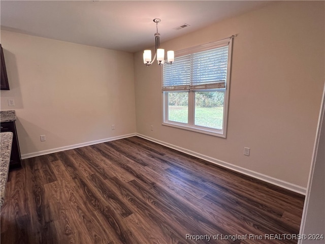 unfurnished dining area with dark hardwood / wood-style flooring and an inviting chandelier