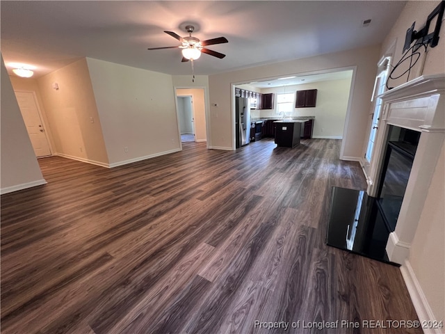 unfurnished living room featuring ceiling fan and dark hardwood / wood-style flooring