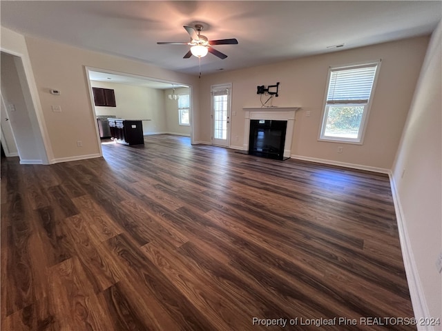 unfurnished living room featuring ceiling fan, plenty of natural light, and dark hardwood / wood-style flooring