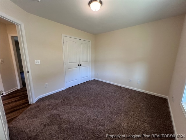 unfurnished bedroom featuring dark colored carpet and a closet