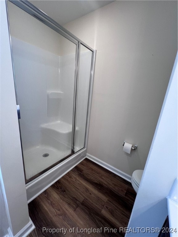 bathroom with toilet, hardwood / wood-style floors, and a shower with door