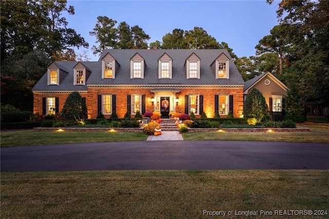 cape cod home featuring a yard