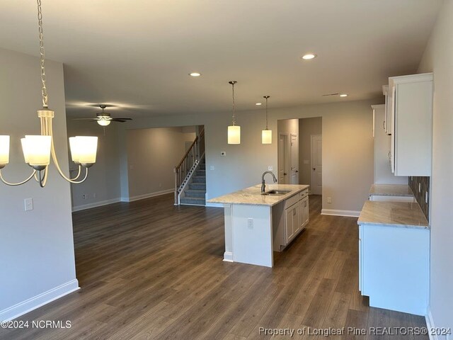 kitchen featuring a kitchen island with sink, dark hardwood / wood-style floors, hanging light fixtures, sink, and white cabinets