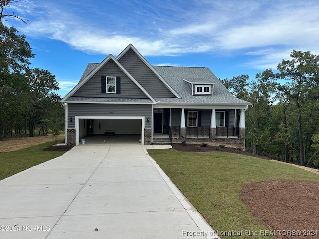 craftsman-style house featuring covered porch, a front yard, and a garage