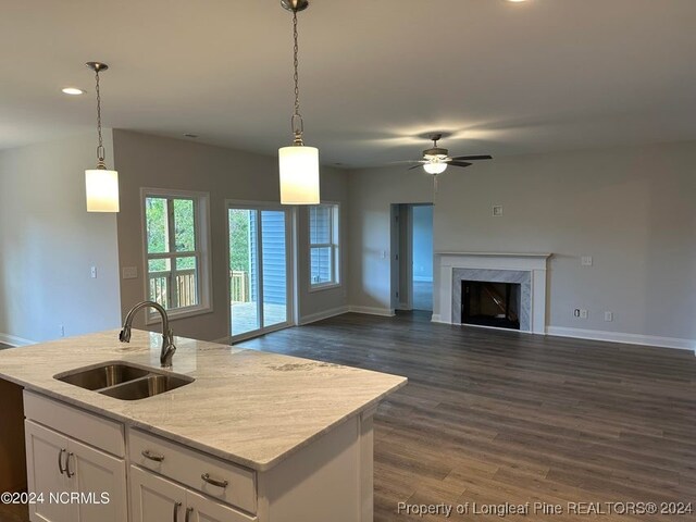 kitchen featuring sink, an island with sink, hanging light fixtures, white cabinetry, and dark wood-type flooring