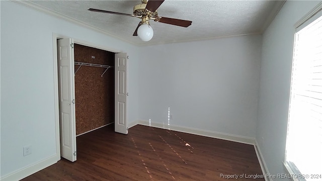 unfurnished bedroom with ornamental molding, ceiling fan, a textured ceiling, a closet, and dark hardwood / wood-style flooring