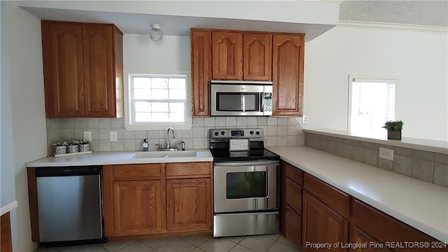 kitchen with tasteful backsplash, ornamental molding, stainless steel appliances, light tile patterned floors, and sink