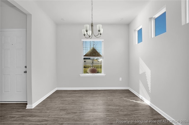 unfurnished dining area featuring dark hardwood / wood-style flooring and a notable chandelier