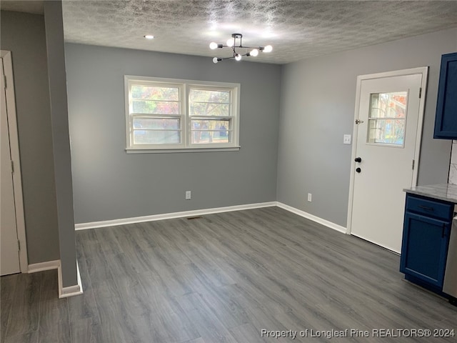 interior space with dark wood-type flooring, an inviting chandelier, and a textured ceiling