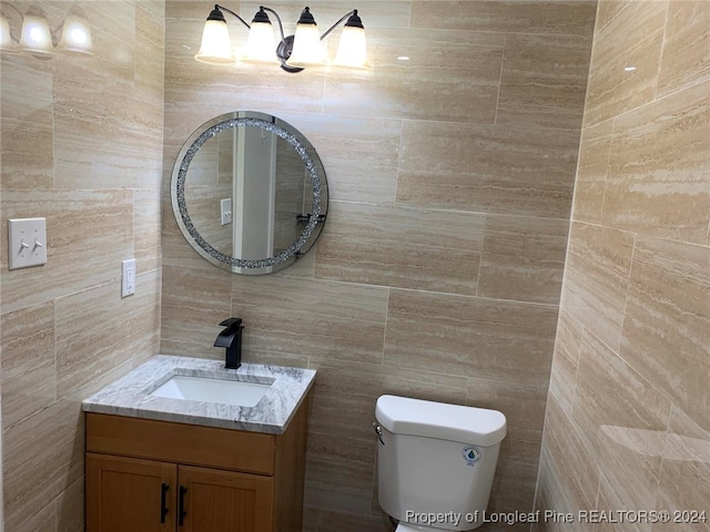 bathroom featuring tile walls, vanity, and toilet