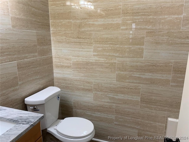 bathroom featuring toilet, vanity, and tile walls