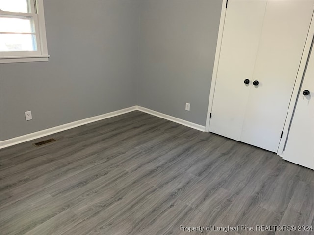 unfurnished bedroom with dark wood-type flooring and a closet